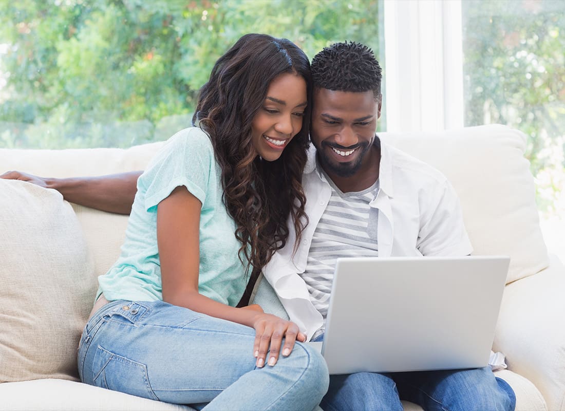 Service Center - Happy Couple on the Couch Using Their Laptop at Home